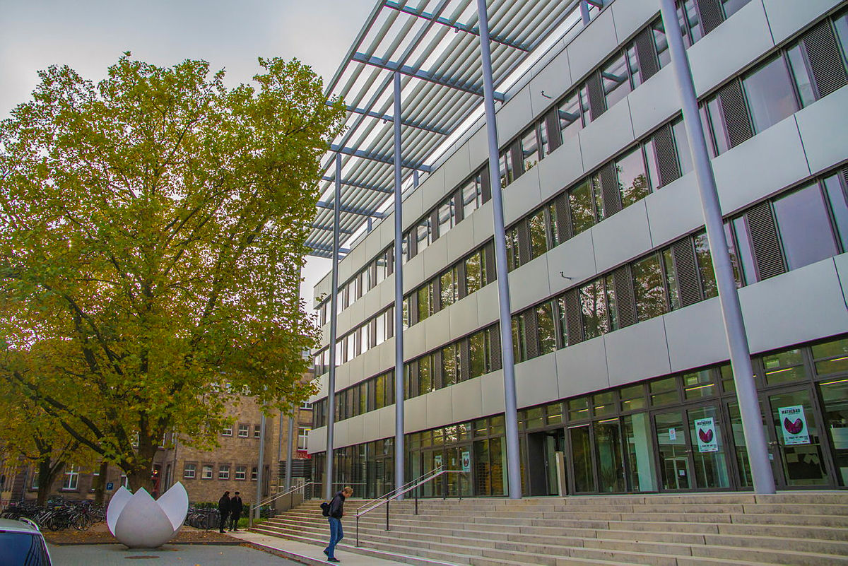 Moderne Bürogebäude mit Glasfassade, Treppenaufgang und Baum im Vordergrund.
